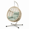 Poltrona sospesa in rattan con supporto in acciaio e cuscini verde menta